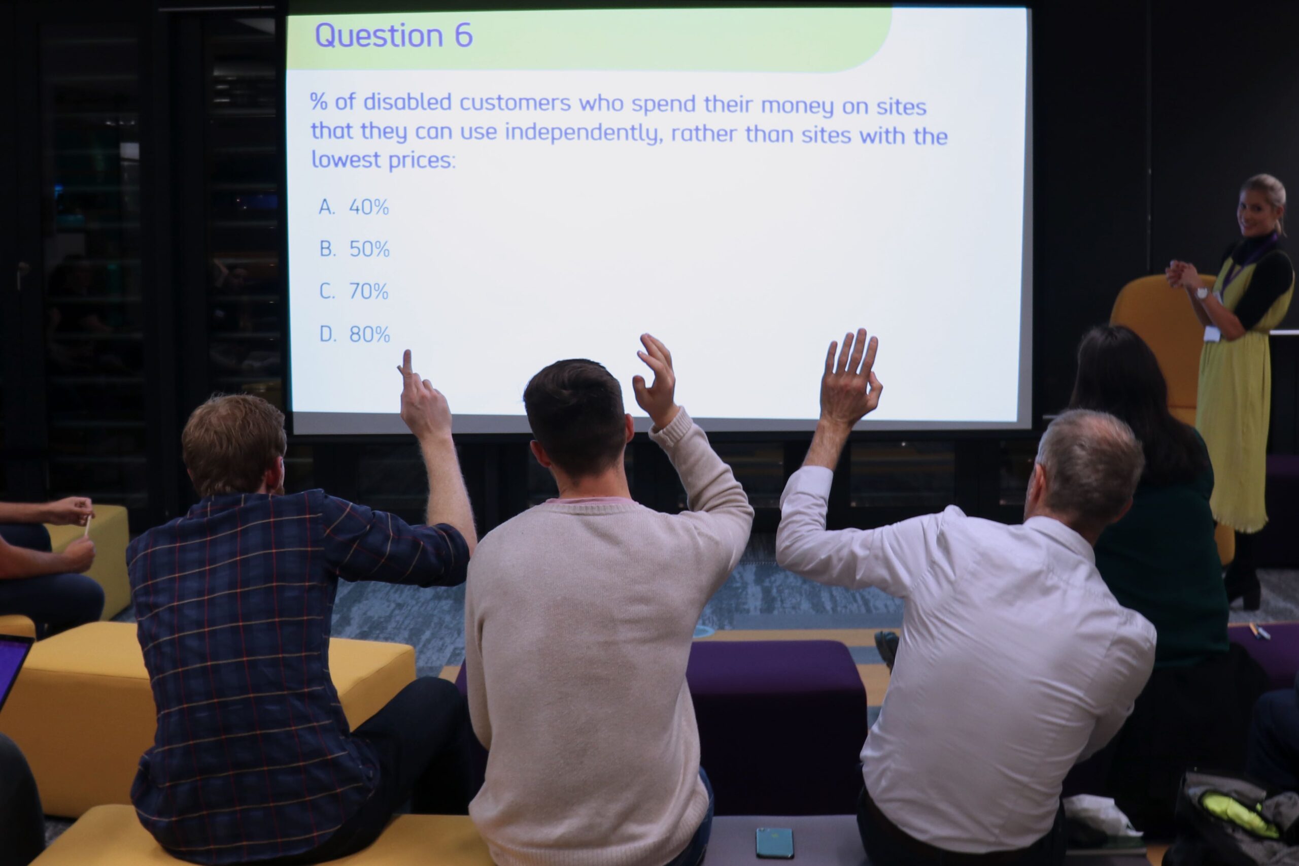 Event attendees raise hand in front of a presentation slide with a question