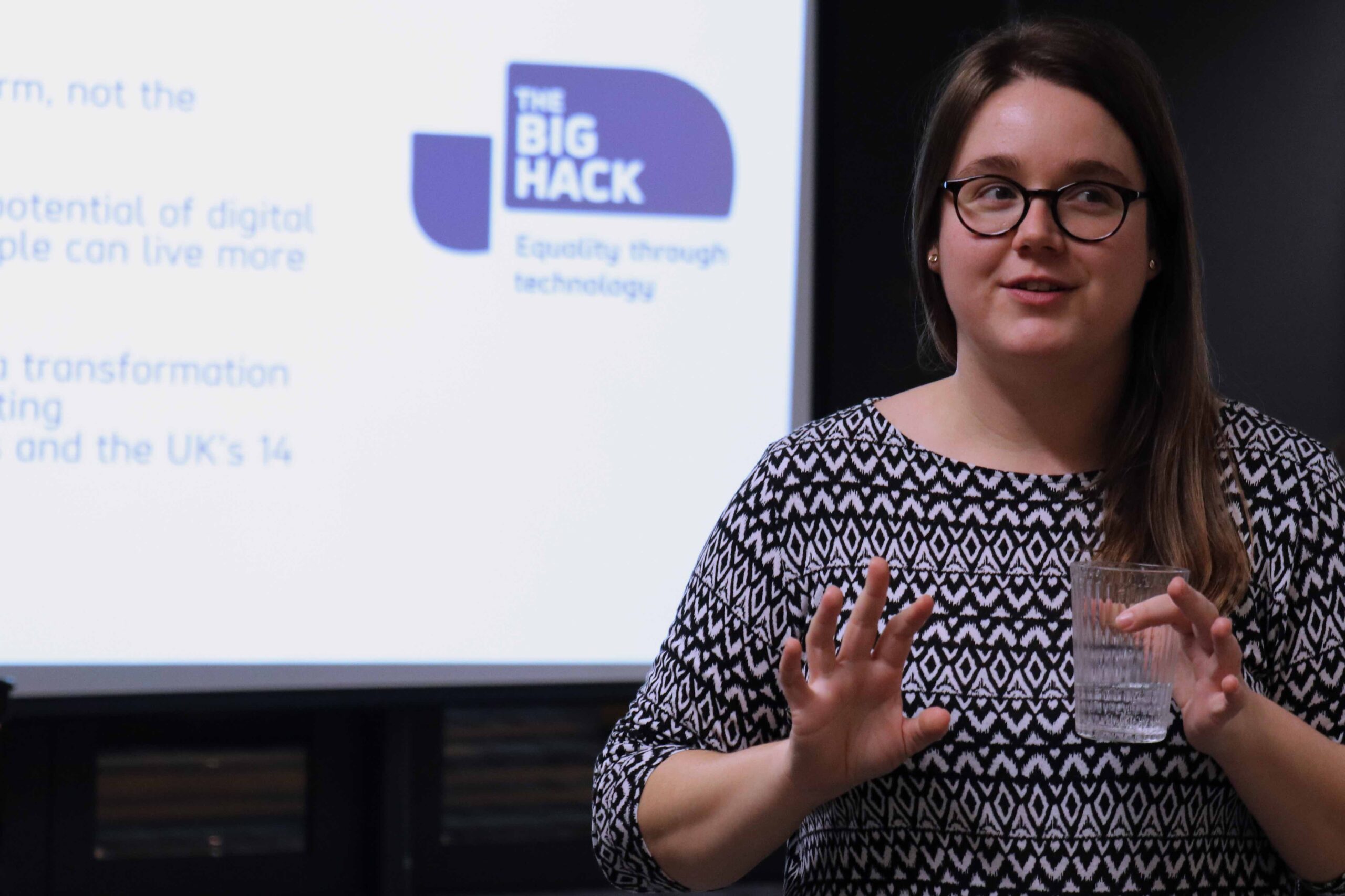 Woman is talking in front of a presentation including The Big Hack logo