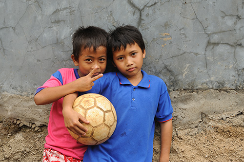 Photograph of two children. One holds a ball