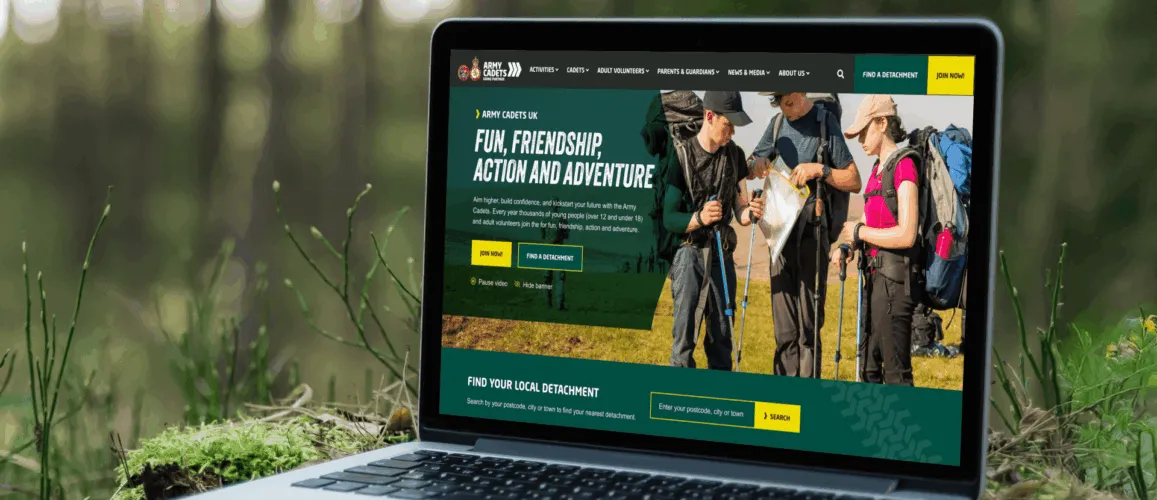 An open laptop in the forest, showing the Army Cadets homepage.